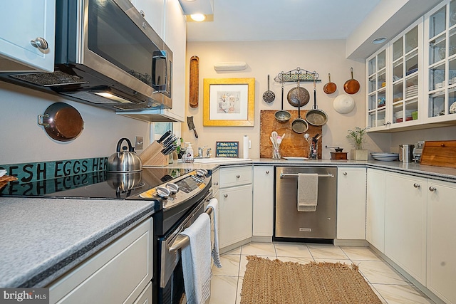 kitchen featuring stainless steel appliances, glass insert cabinets, and white cabinets