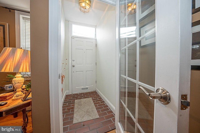 doorway to outside with baseboards and brick floor