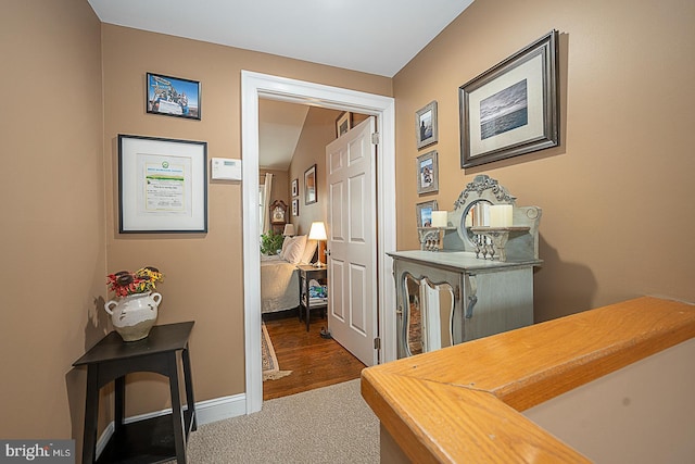 hallway featuring baseboards and dark carpet