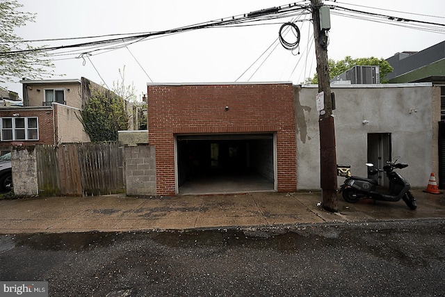 view of front of house with brick siding, an outdoor structure, a garage, and fence