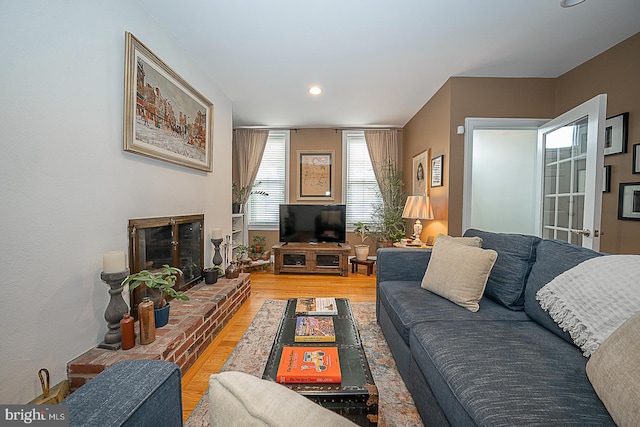 living area with light wood finished floors, recessed lighting, and a brick fireplace