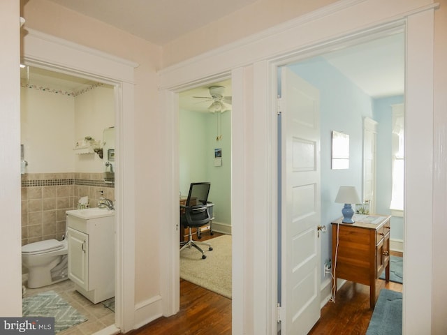 corridor featuring a sink, tile walls, and wood finished floors