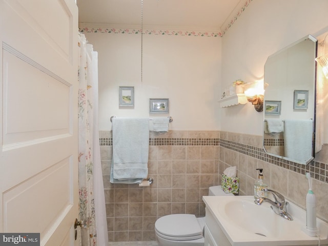 full bath with vanity, tile walls, toilet, and wainscoting