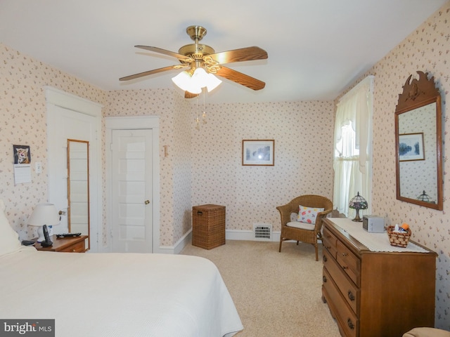 bedroom featuring visible vents, light carpet, wallpapered walls, baseboards, and ceiling fan