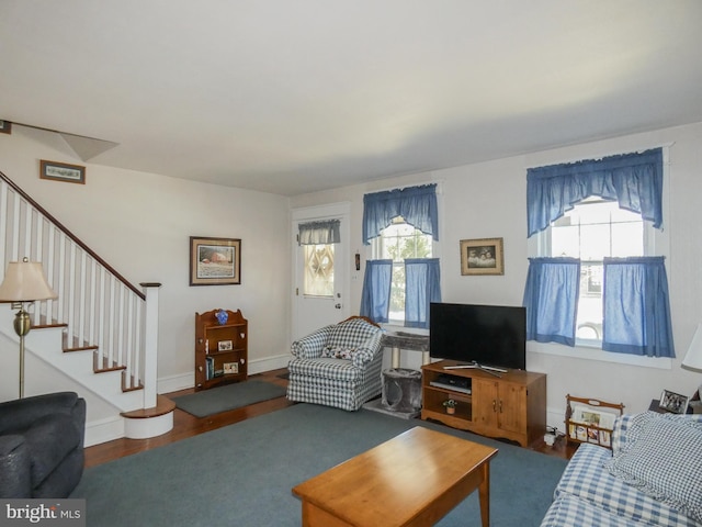 living area with a wealth of natural light, stairway, baseboards, and wood finished floors