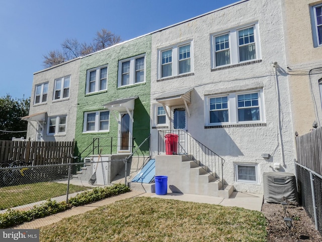 townhome / multi-family property with fence, central AC, and stucco siding