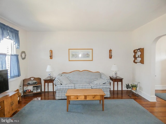 living room with baseboards, arched walkways, and wood finished floors