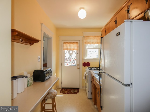 kitchen featuring brown cabinetry, white appliances, and light countertops