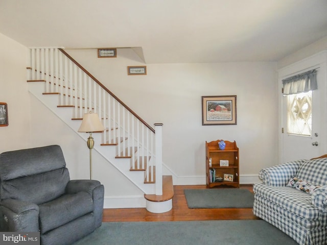 living area with stairway, baseboards, and wood finished floors