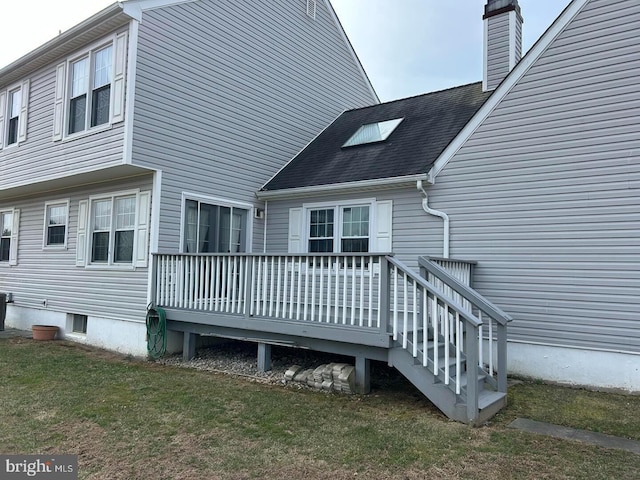 back of house with a wooden deck, a chimney, and a yard