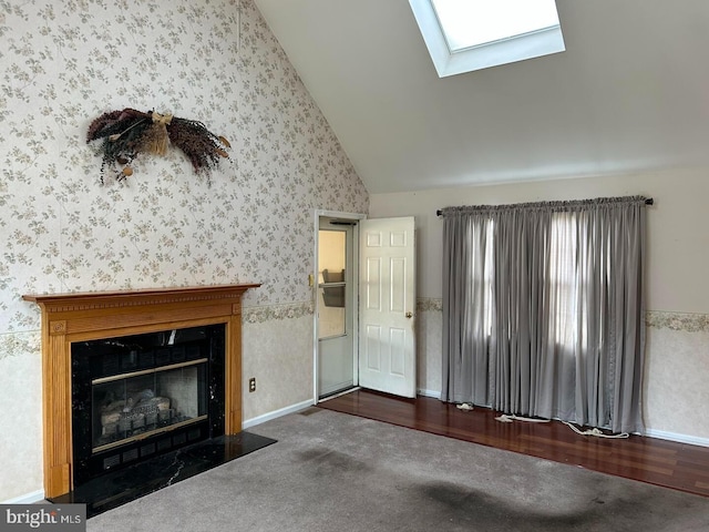 unfurnished living room featuring lofted ceiling with skylight, carpet floors, a fireplace with flush hearth, and wallpapered walls