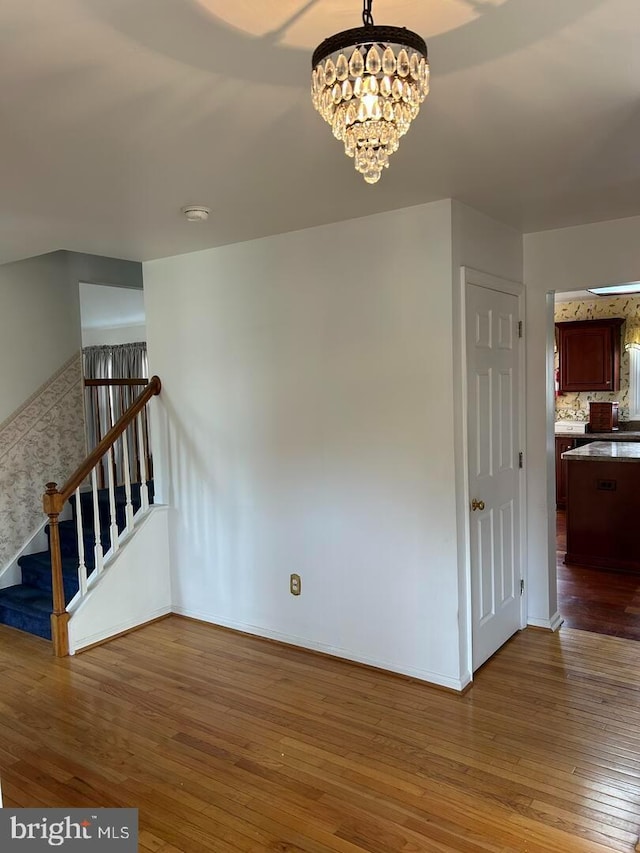 interior space featuring a chandelier, stairway, baseboards, and hardwood / wood-style flooring