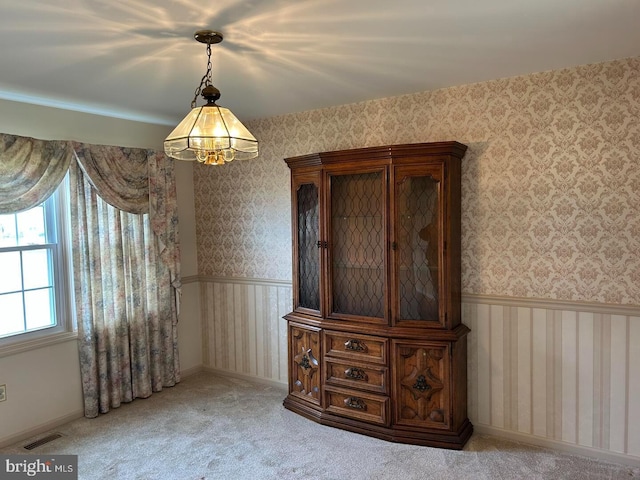 unfurnished dining area featuring visible vents, wainscoting, and wallpapered walls