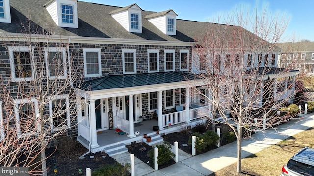 view of front of house with a porch, stone siding, and a shingled roof