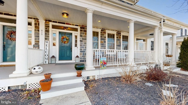 view of exterior entry featuring stone siding and a porch