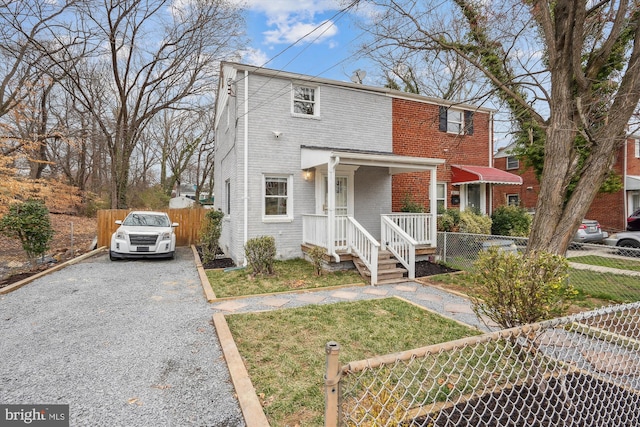 traditional-style home with driveway, brick siding, a front lawn, and fence