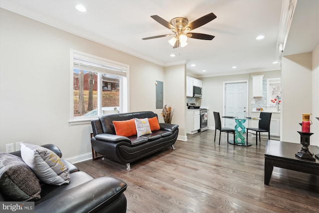 living area with ornamental molding, ceiling fan, baseboards, and wood finished floors