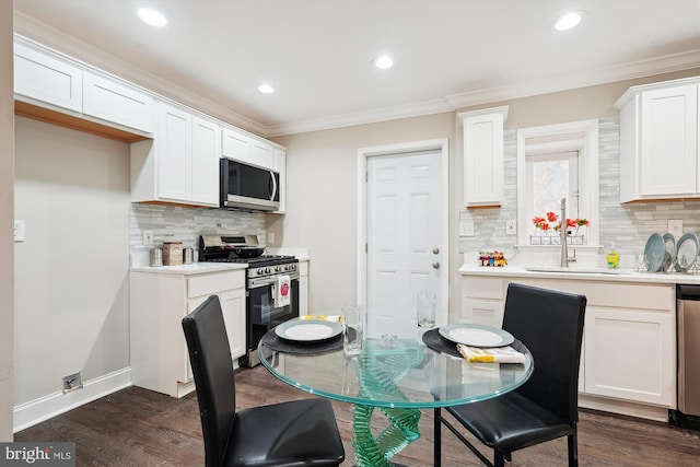 kitchen with dark wood-style floors, white cabinets, appliances with stainless steel finishes, and crown molding