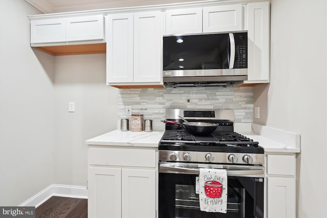 kitchen featuring baseboards, light stone counters, decorative backsplash, appliances with stainless steel finishes, and white cabinets