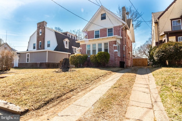 view of front facade with brick siding and a chimney