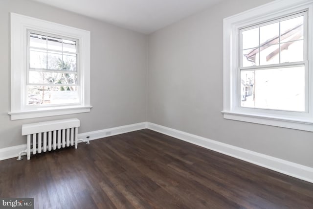 unfurnished room with baseboards, dark wood-type flooring, and radiator heating unit