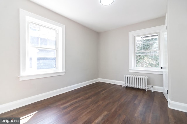 unfurnished room with baseboards, radiator, and dark wood finished floors