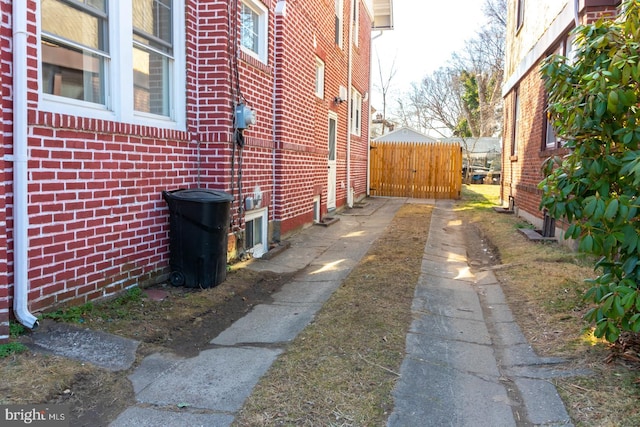 view of side of home with fence and brick siding