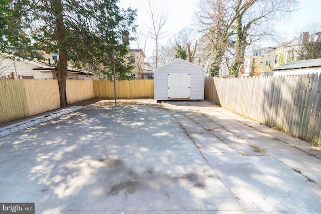 view of patio with an outbuilding, a storage unit, and a fenced backyard