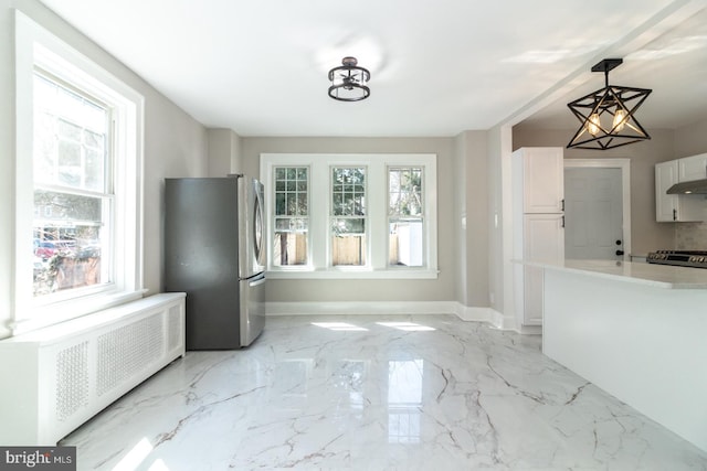 kitchen with marble finish floor, stainless steel appliances, radiator, light countertops, and baseboards