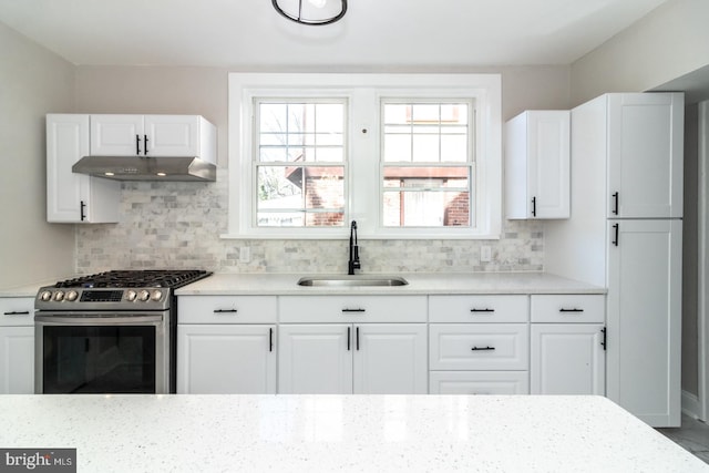 kitchen featuring backsplash, stainless steel range with gas stovetop, under cabinet range hood, and a sink