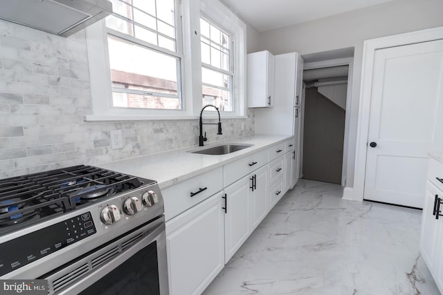 kitchen with marble finish floor, a sink, tasteful backsplash, white cabinets, and gas range