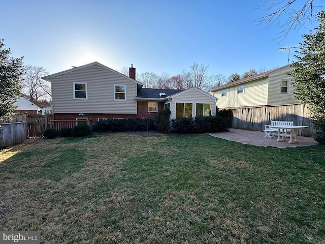 back of house with a chimney, a patio area, fence, and a lawn