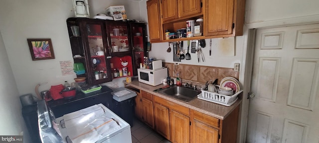 kitchen featuring open shelves, a sink, brown cabinetry, washer / dryer, and white microwave
