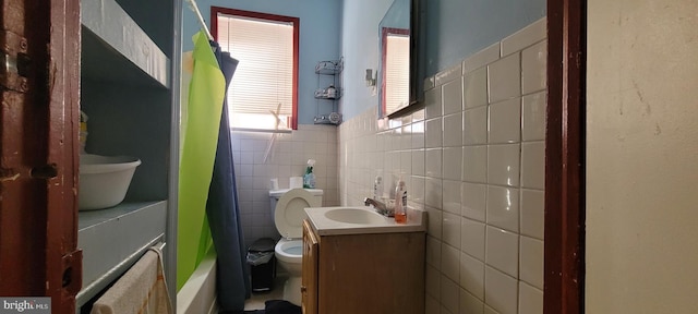 full bathroom featuring vanity, wainscoting, toilet, and tile walls