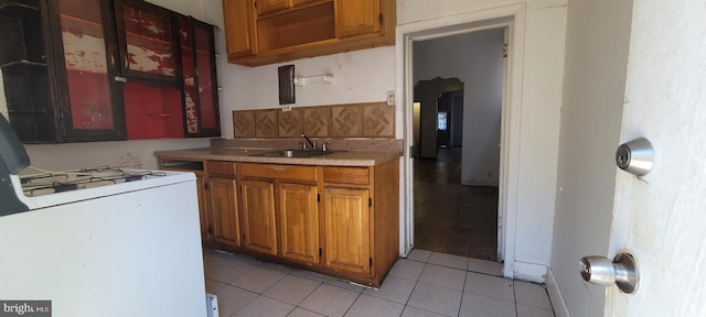 kitchen with open shelves, a sink, brown cabinetry, light tile patterned floors, and range with gas cooktop