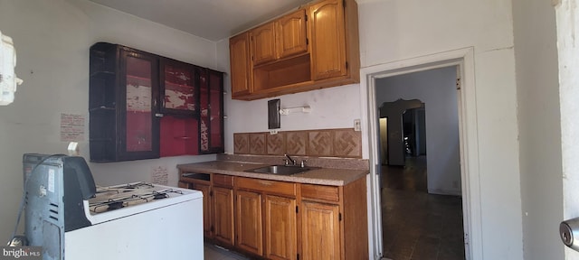 kitchen with brown cabinets, white gas range oven, a sink, and light countertops