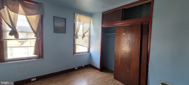 unfurnished bedroom featuring baseboards, light wood finished floors, and a closet
