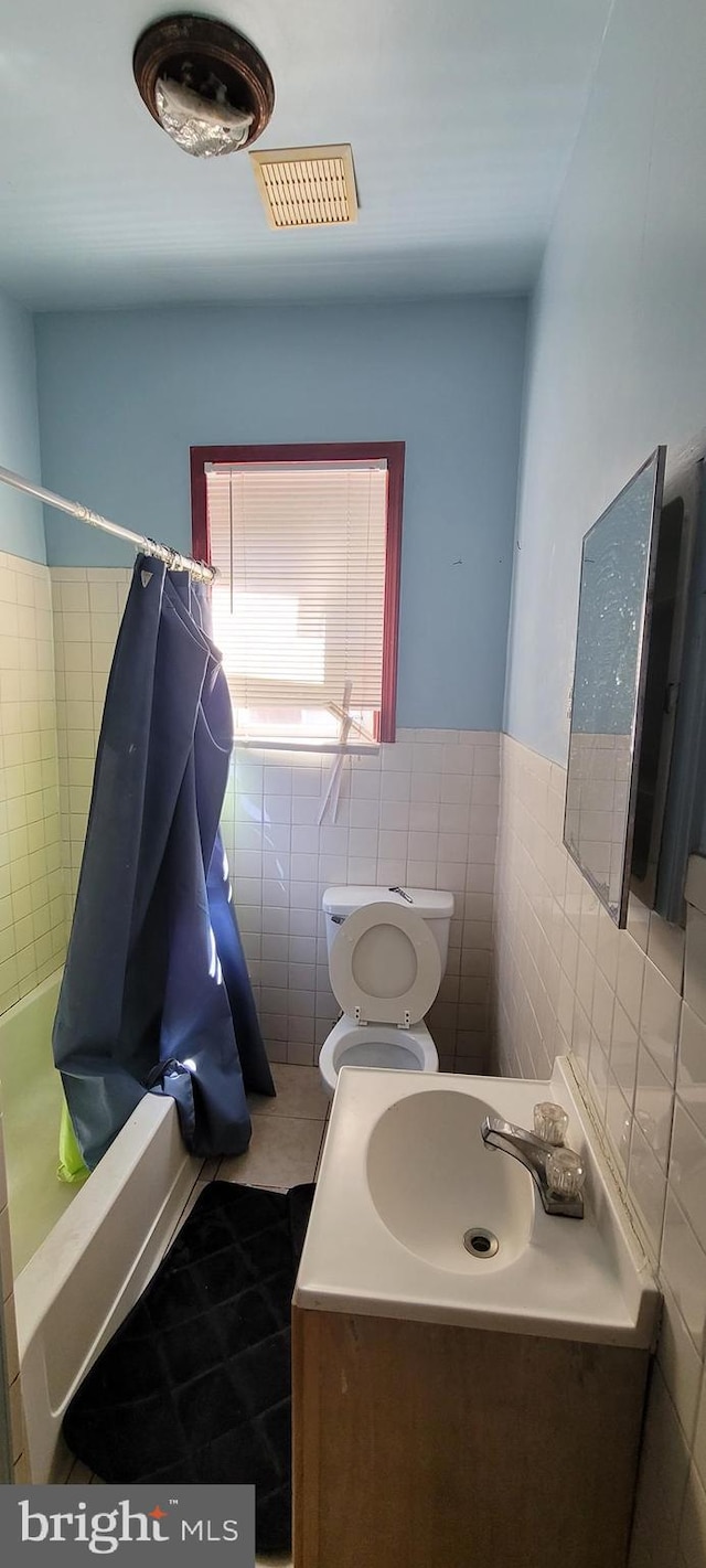 bathroom with tile walls, tile patterned floors, a wainscoted wall, vanity, and toilet