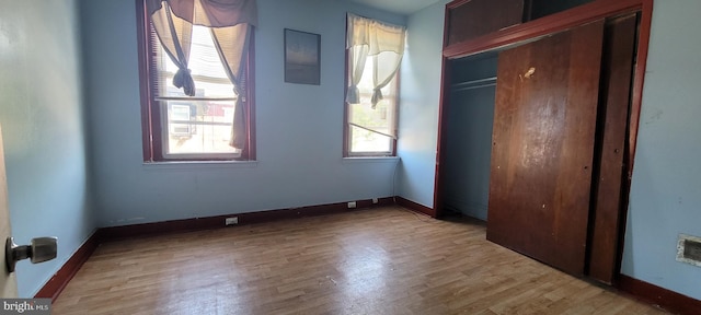 unfurnished bedroom with baseboards, light wood finished floors, and a closet