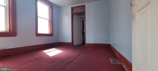 unfurnished bedroom featuring visible vents, carpet flooring, baseboards, and multiple windows