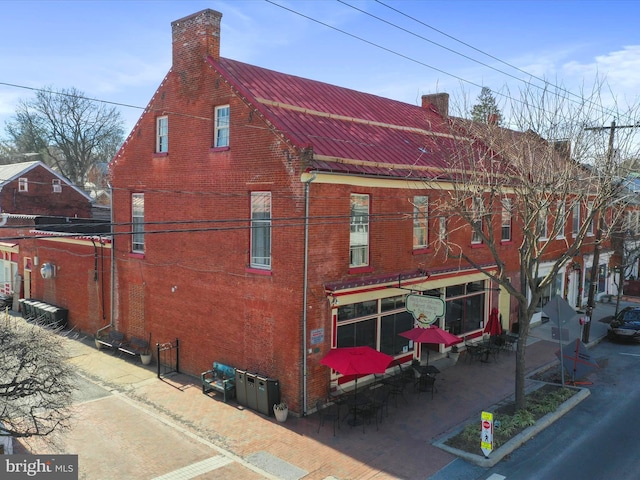 view of property exterior with brick siding and a chimney