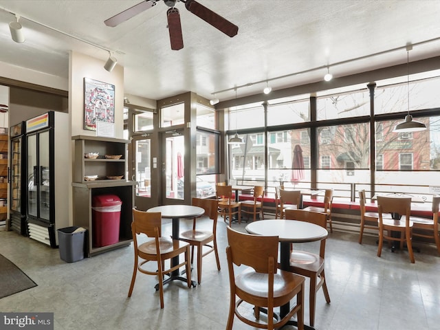 dining space featuring track lighting, a textured ceiling, and a ceiling fan