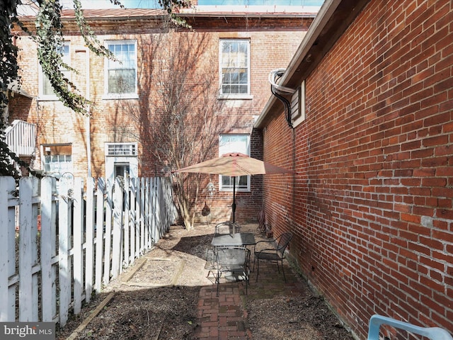 view of side of property featuring brick siding, a patio, and fence