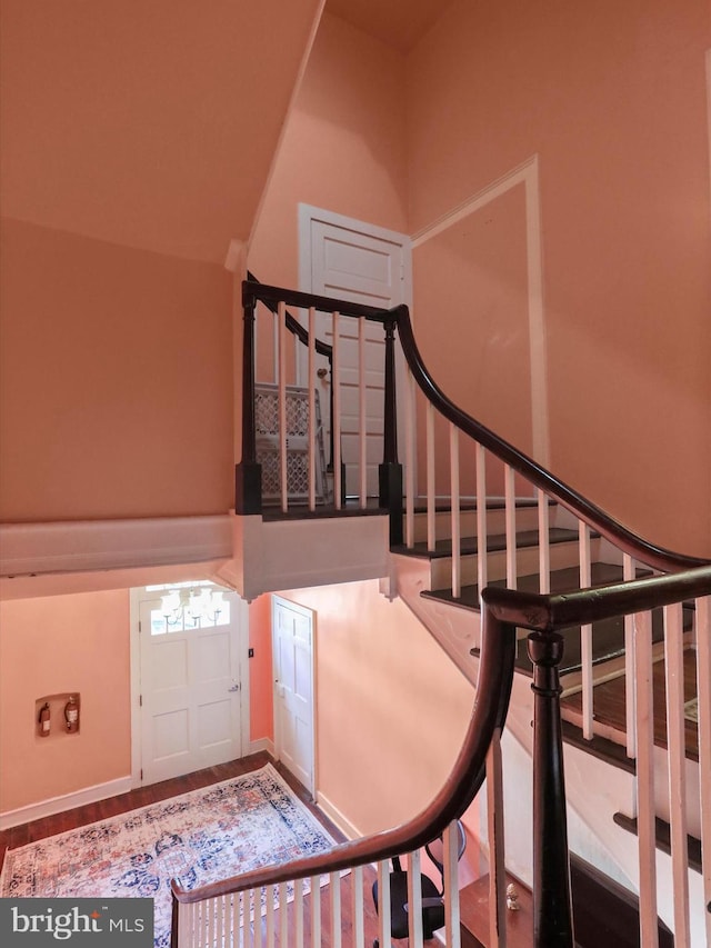 staircase with vaulted ceiling and wood finished floors