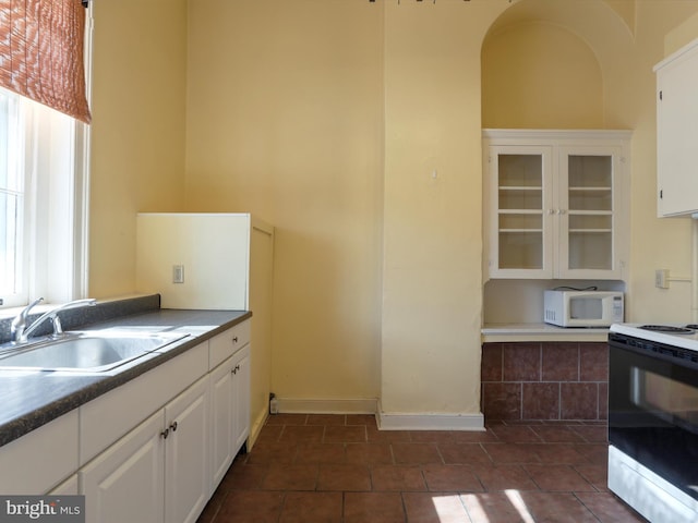 kitchen featuring a sink, range with electric stovetop, white cabinets, glass insert cabinets, and white microwave