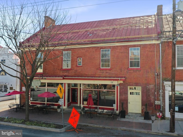 back of house featuring brick siding, a chimney, and entry steps