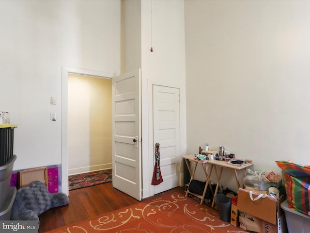 home office featuring a high ceiling and hardwood / wood-style flooring