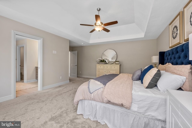 bedroom with light carpet, ceiling fan, baseboards, and a tray ceiling