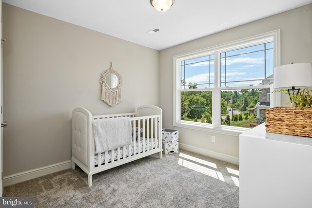 carpeted bedroom with a nursery area, baseboards, and visible vents