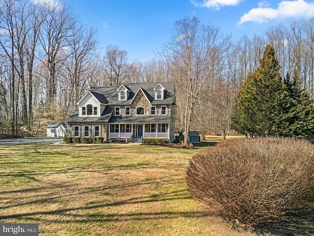 shingle-style home with an outbuilding, a porch, and a front lawn